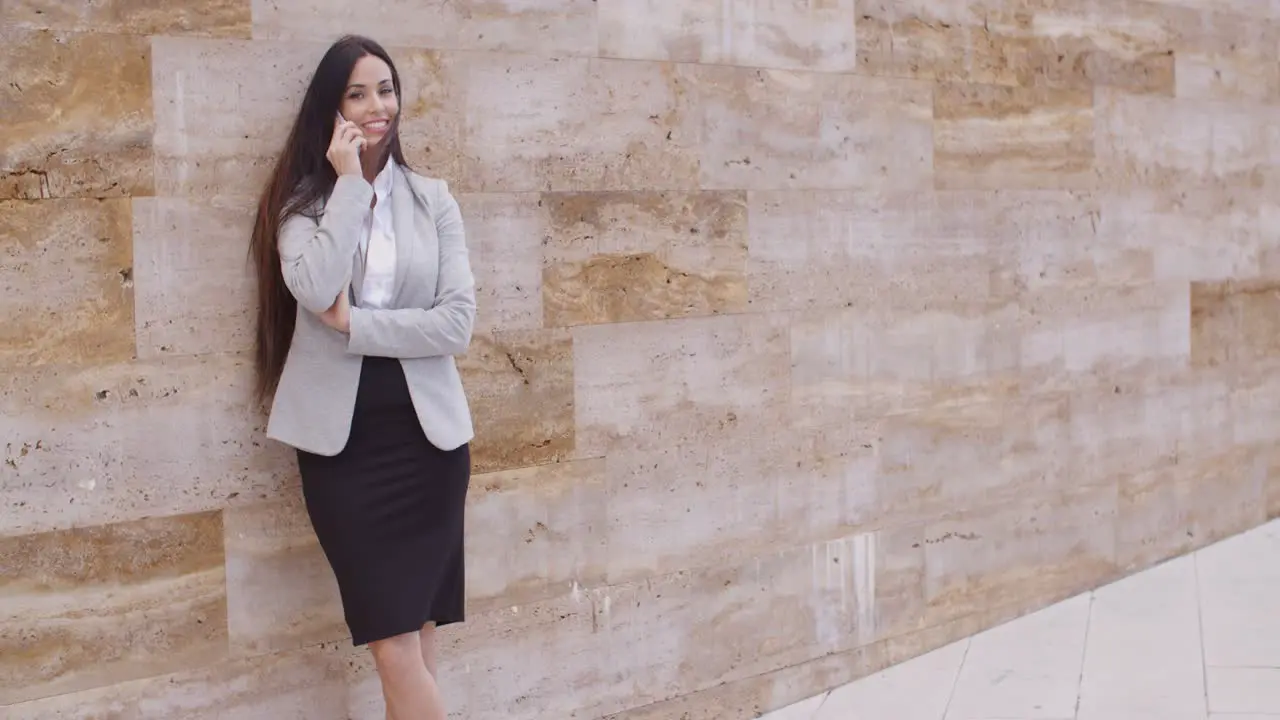 Pretty woman talking on phone and leaning on wall