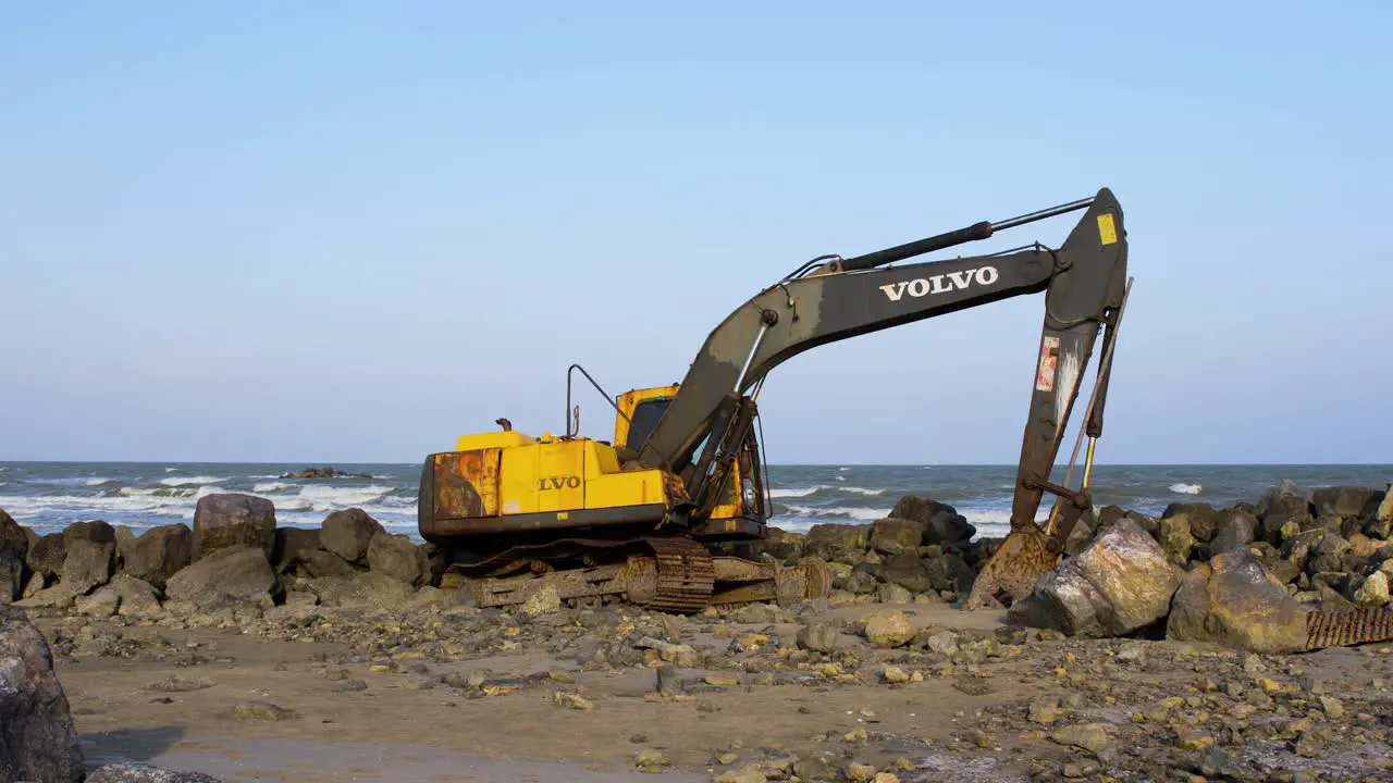 Abandoned Yellow Digger Machinery on Rocky Beach Thailand