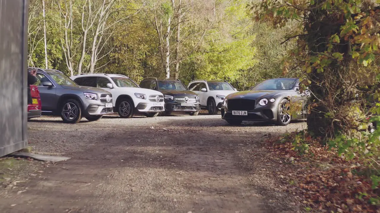 Push in Reveal shot of Car dealership parking lot amidst urban forest Aerial Low angle