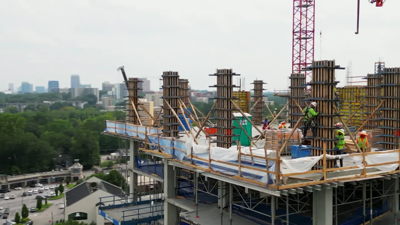 Aerial slide and pan footage of construction workers performing dangerous tasks high above ground