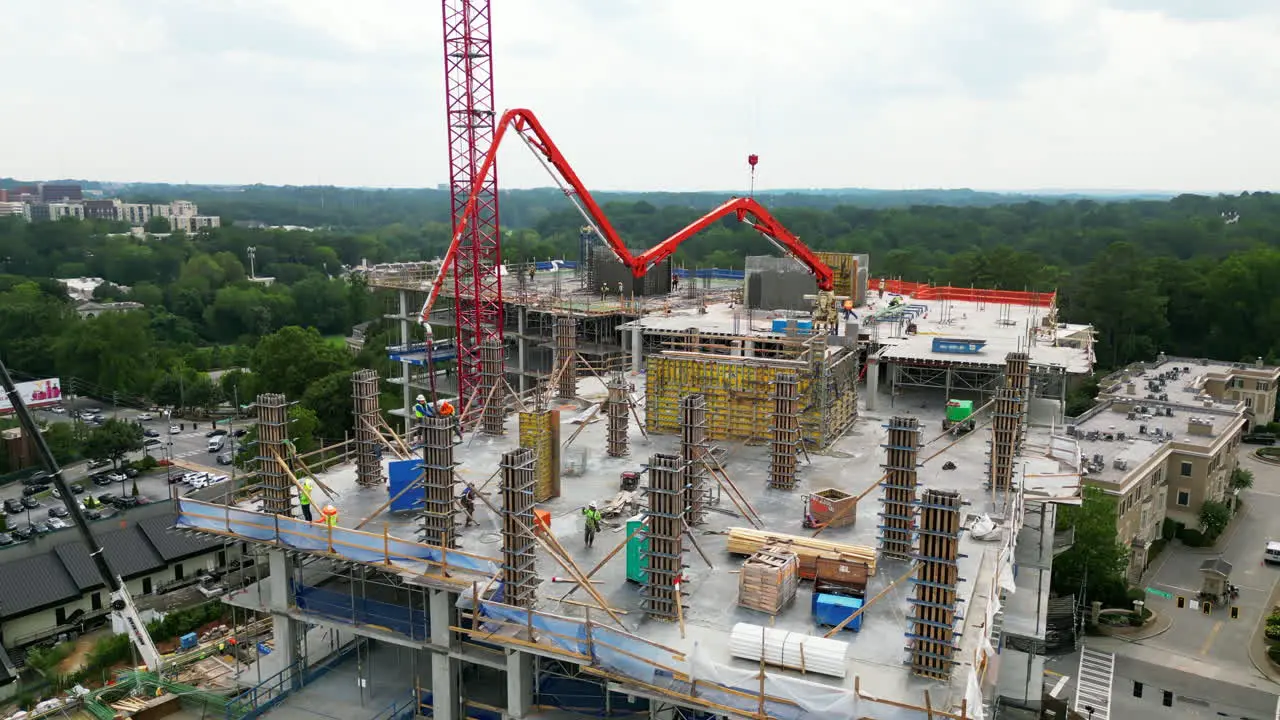 Aerial ascending footage of workers casting concrete columns to framework