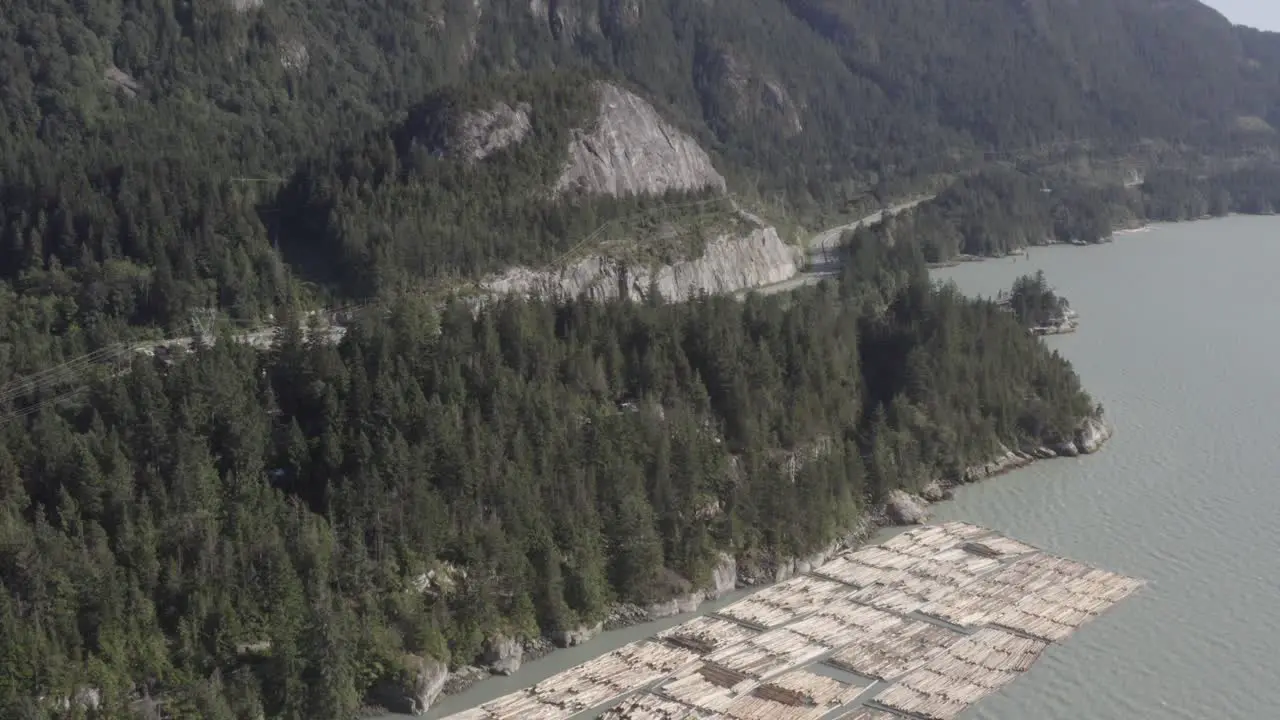 Aerial fly over ocean mineral bay harbor of lumber industry export dock of inventory stacked for preperation to board tug boats to the freightor port of cargo transportaion on a clear summer day 4-4