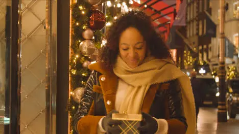 Woman Walking Along Street On Christmas Shopping Trip To London Holding Present Or Gift