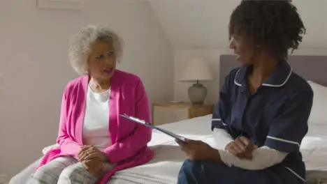 Middle Aged Nurse Conducting a Home Visit with Senior Woman