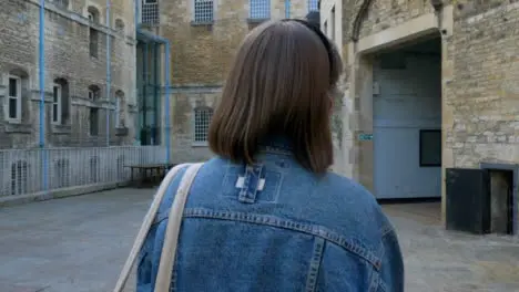 Tracking Shot Following Young Woman Walking Past Oxford Prison