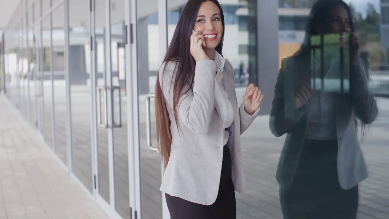 Happy business woman on phone next to window