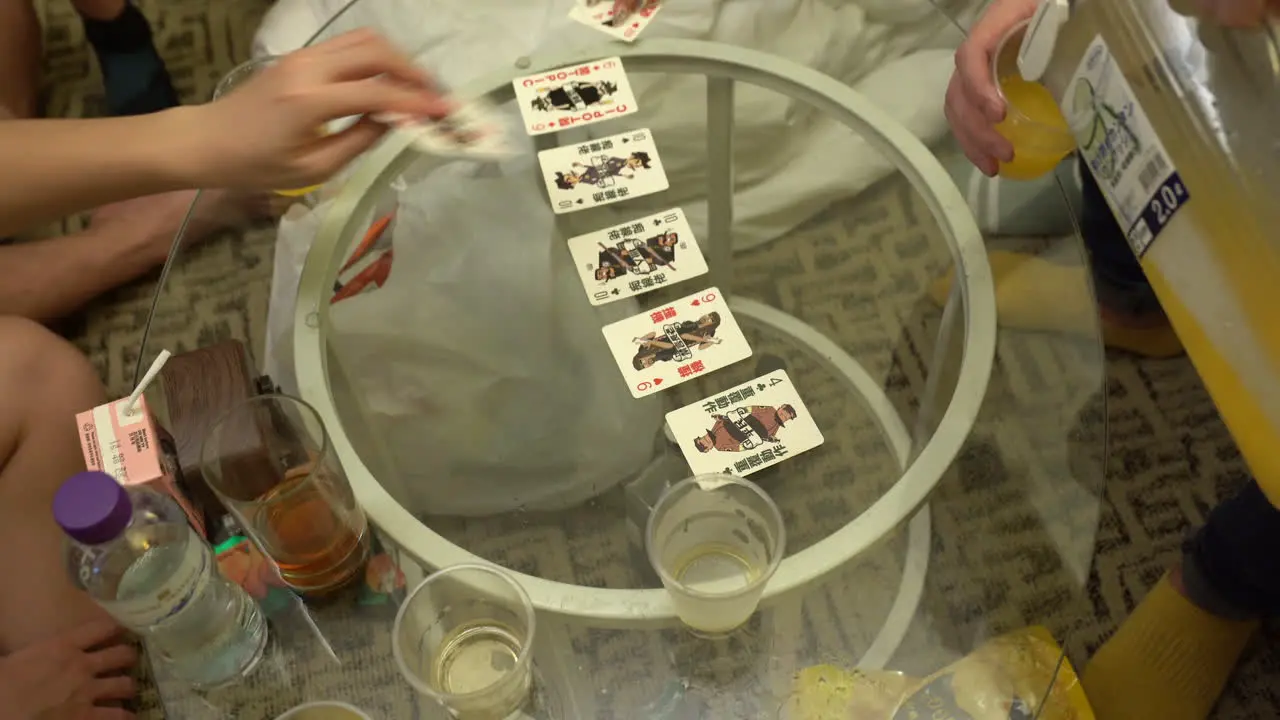 Unidentifiable asian people play a typical card game in hong kong on a glass table