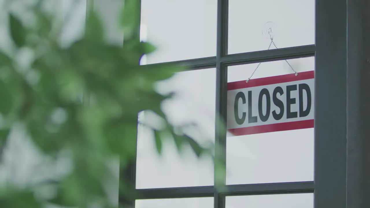 A hanging sign in a window that indicates the business is open until it is flipped over to show closed