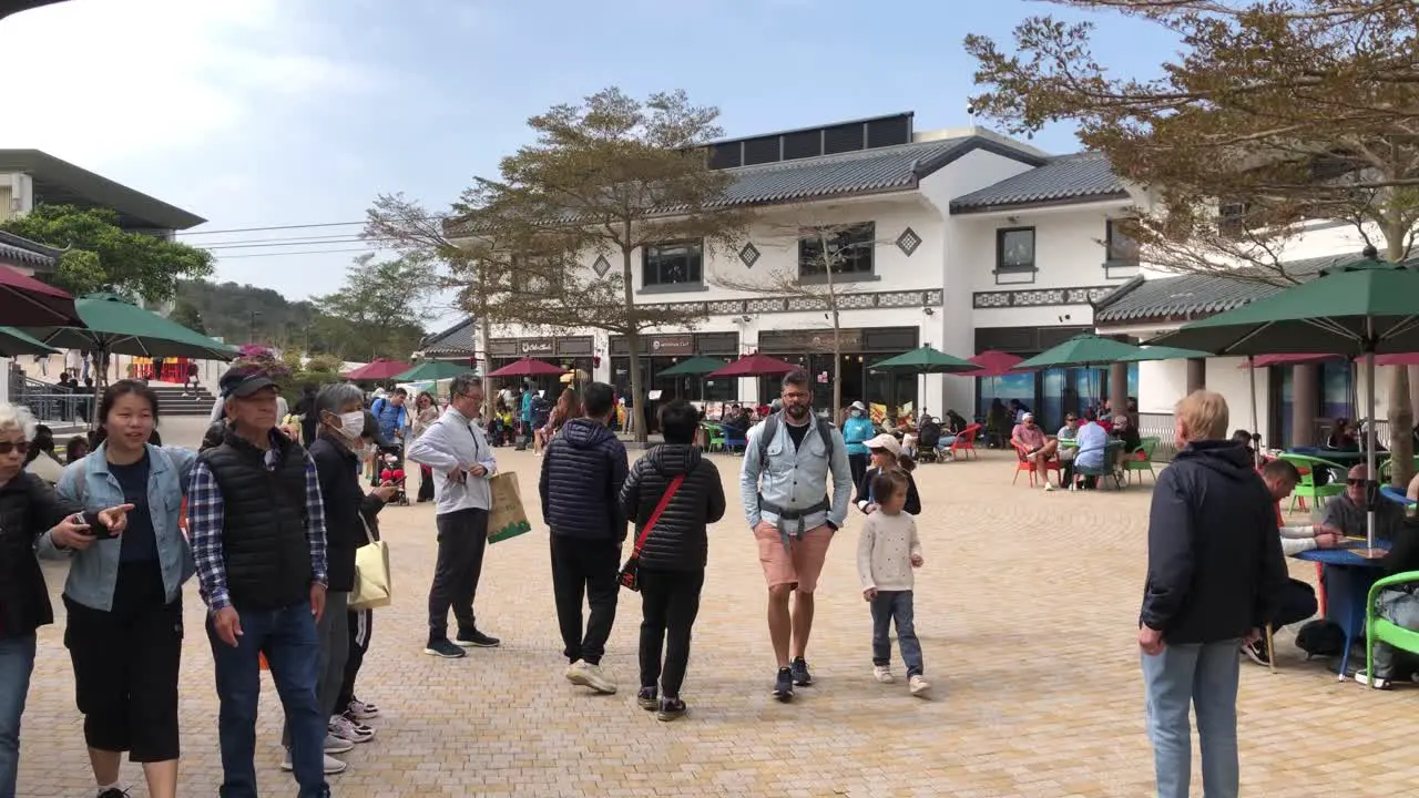 People enjoy the restaurant area on a sunny day in Ngong Ping Village Lantau Island Hong Kong