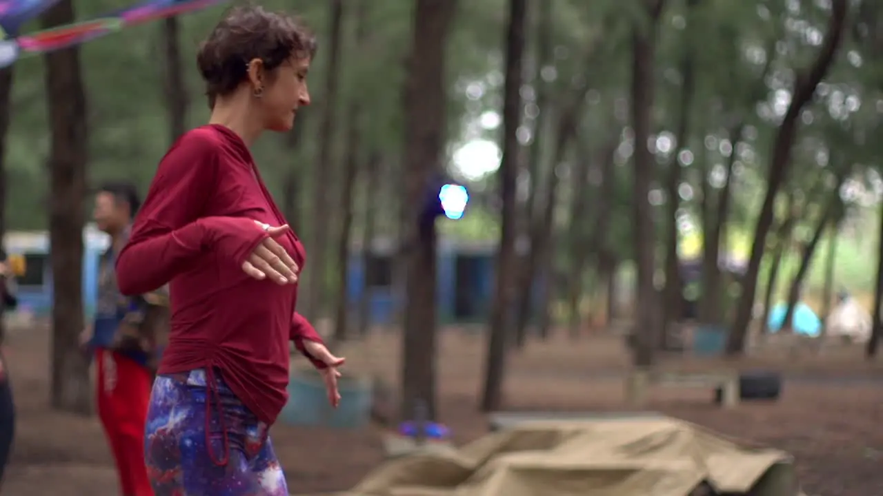 Caucasian woman dressed in red top dancing ecstatically in outdoor festival filmed in slow motion handheld style as medium shot