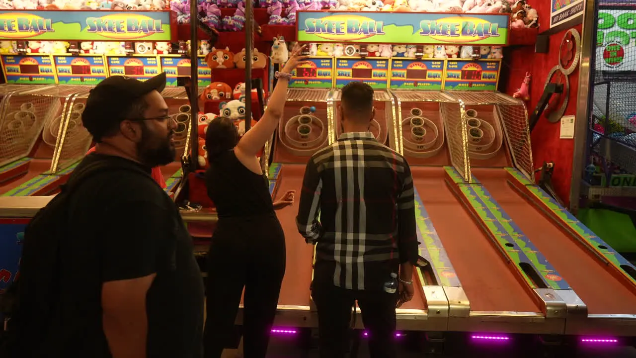 A couple plays a skee-ball arcade game during a fun evening out at a carnival