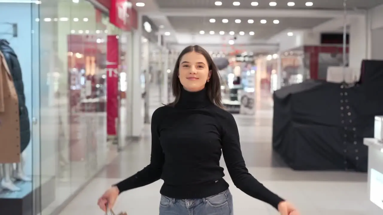 young girl with packages after shopping spins walking in the mall