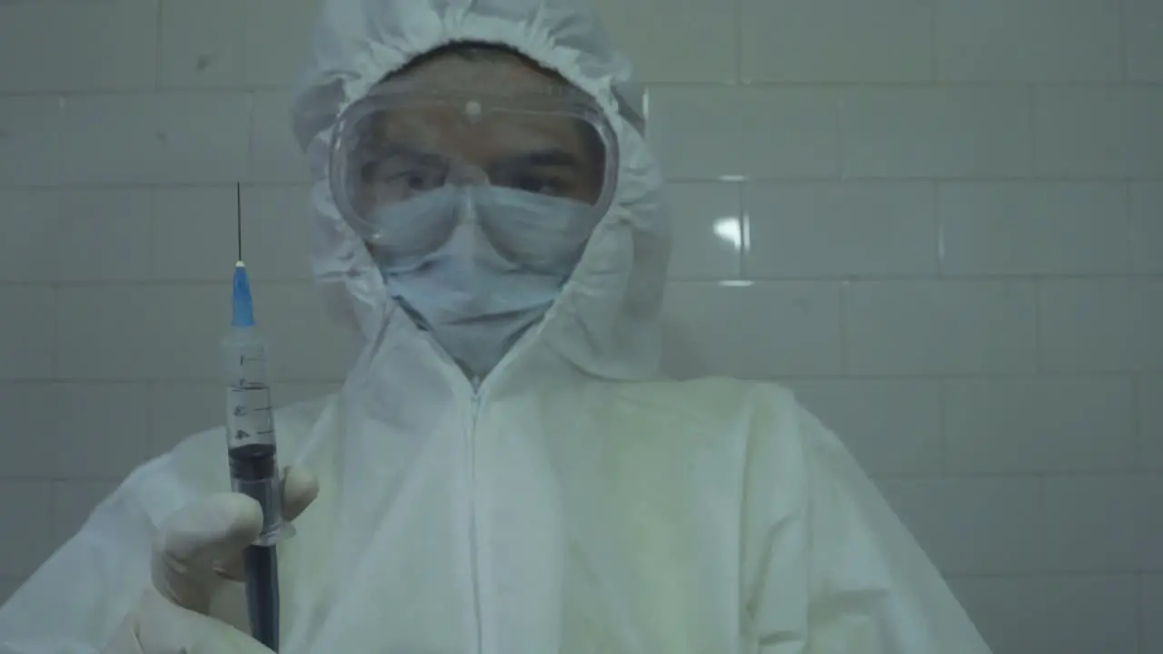 medical doctor wearing protective PPE spilling out medicine off a syringe after filling it with covid 19 vaccine