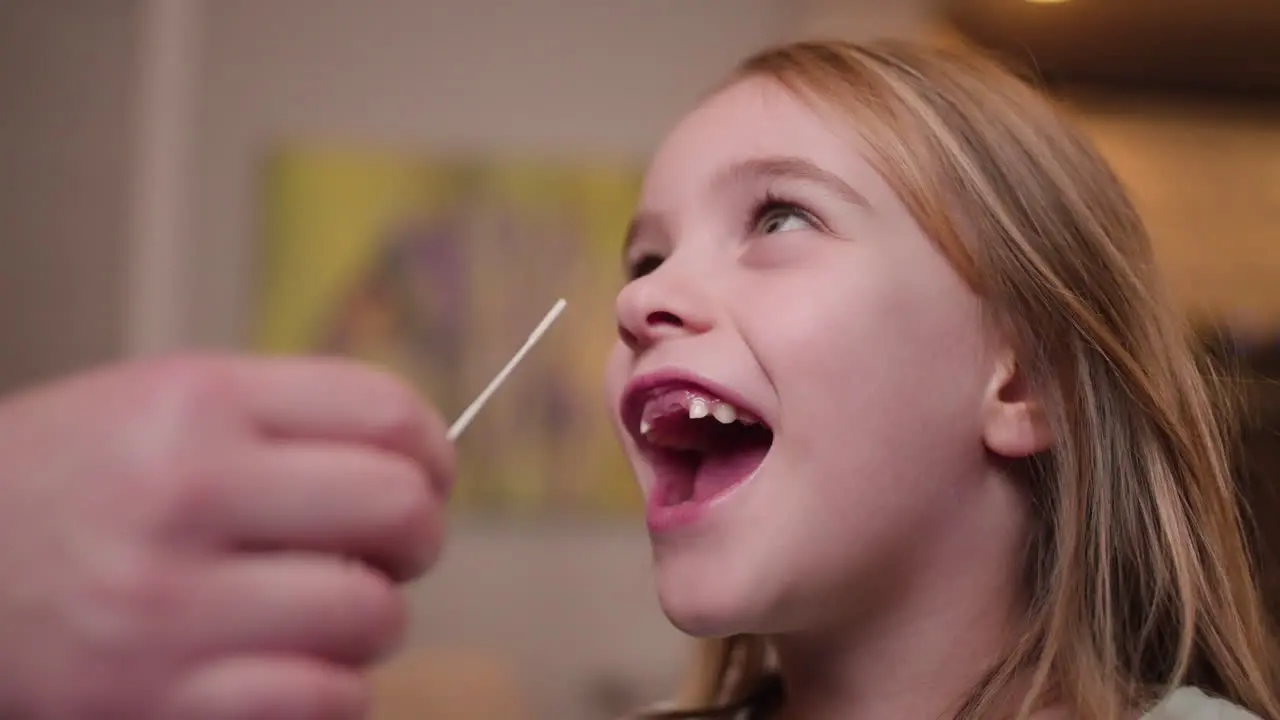 A young girl laughs her way through a COVID-19 nasal swab for a rapid antigen test