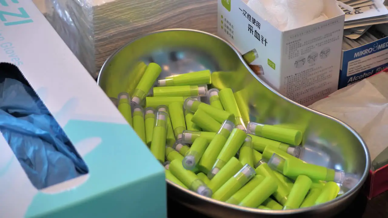 Slow motion shot of a silver kidney dish full of blood glucose monitoring needles