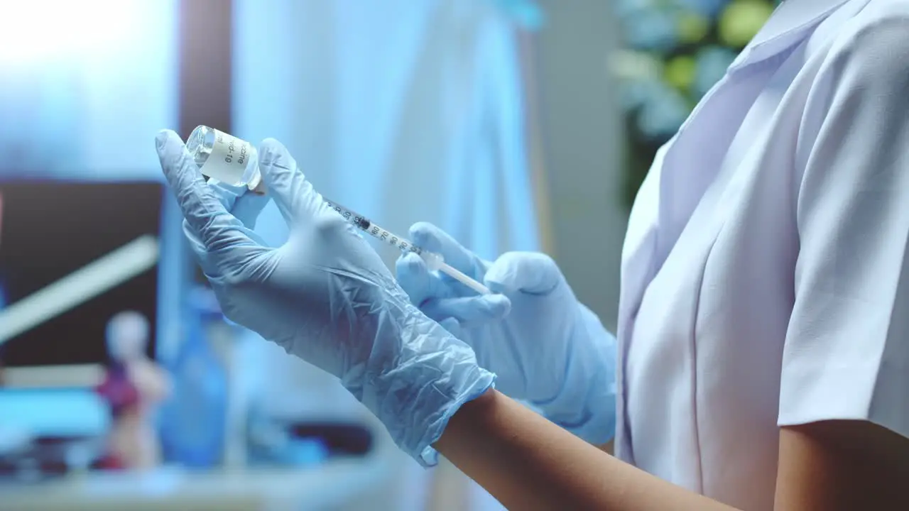 A nurse measures out a dose of COVID vaccine to give a shot to a patient