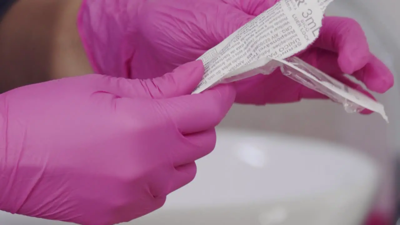 Opening a syringe to prepare a Botox injection isolated close up of female doctor hands and needle