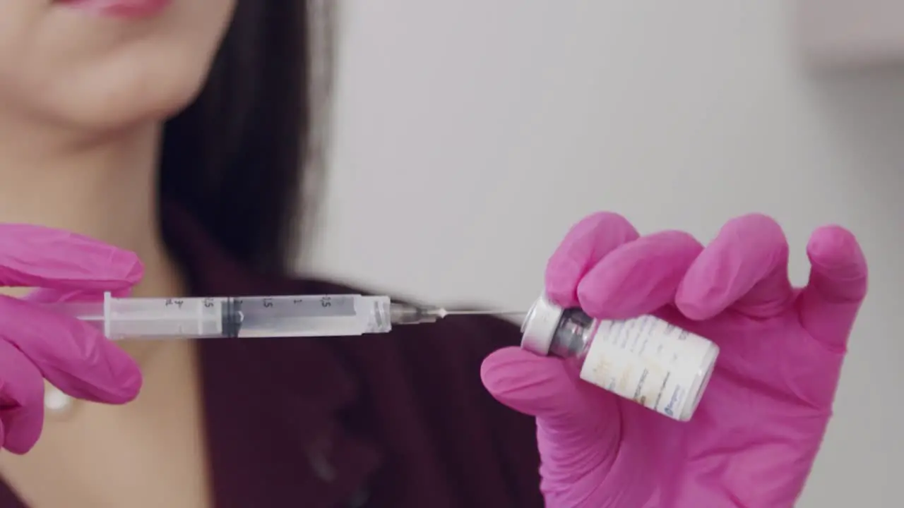 Young Hispanic female doctor filling a syringe from a vial