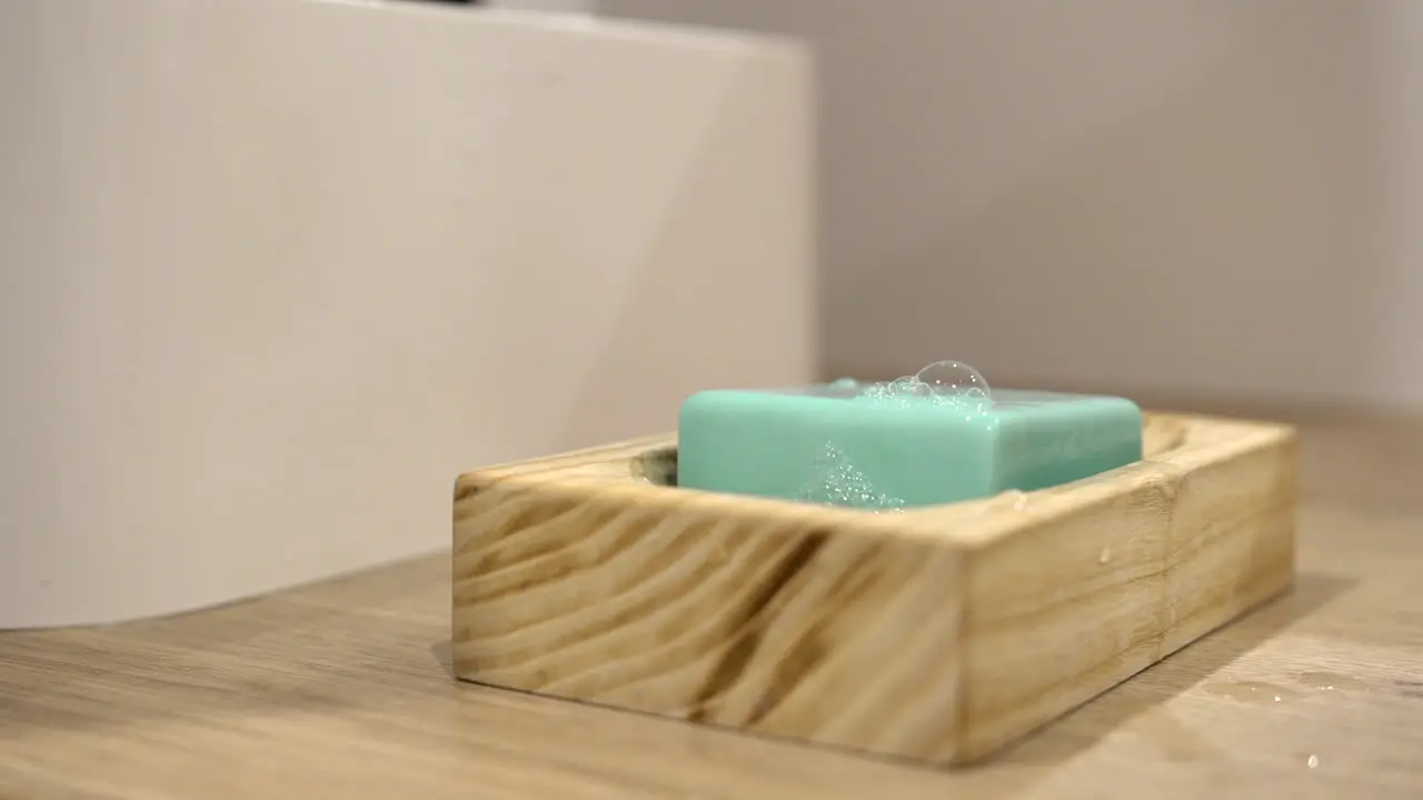 Taking green soap from beautiful wooden pedestal and putting it back wet