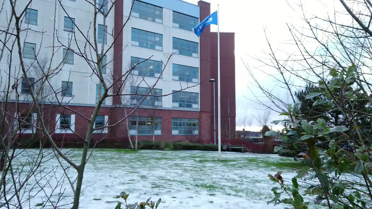 Rising up NHS flag waving proudly outside a snowy hospital symbolizing the strength and resilience of the UK's healthcare system