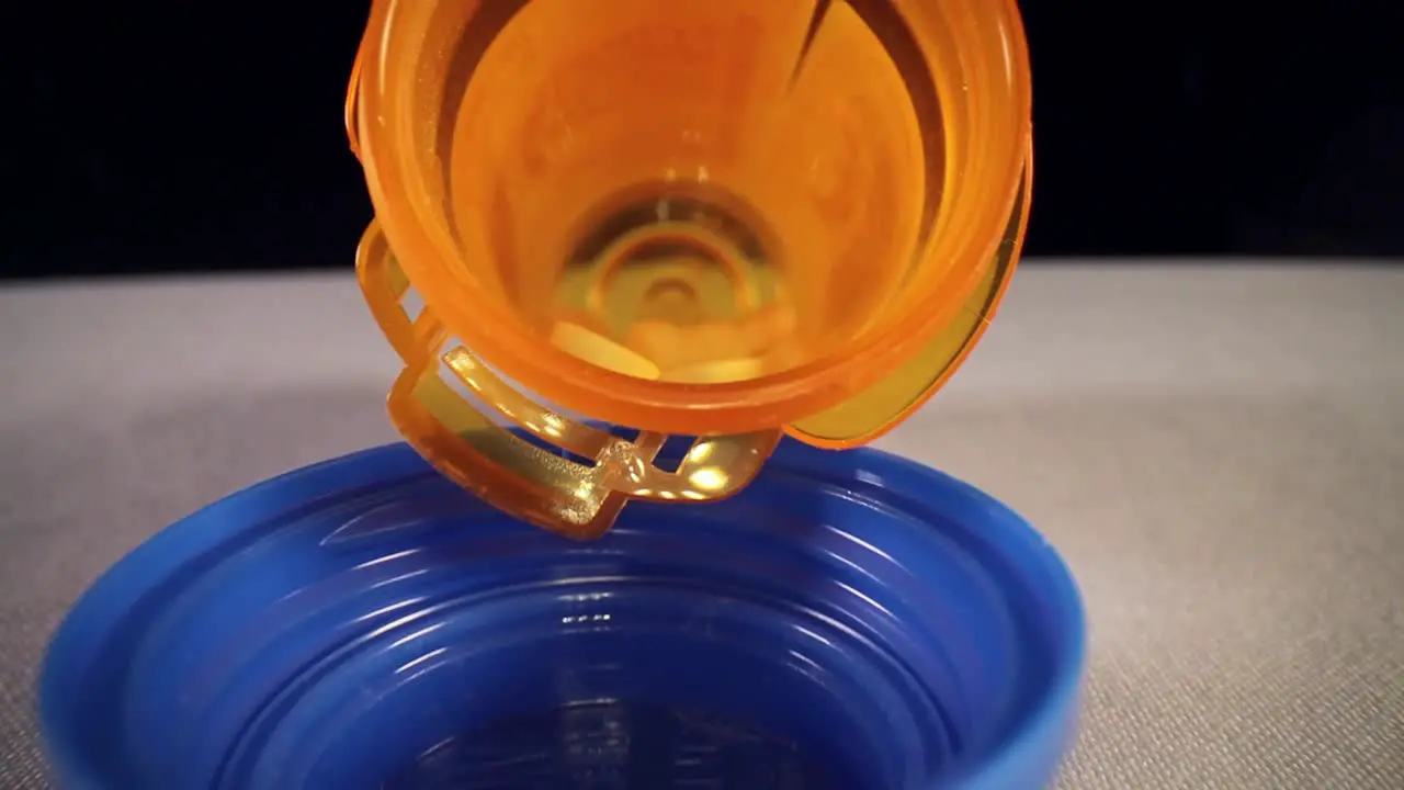 quickly pulling out of the entire length of a orange prescription pill bottle revealing empty blue bottle cap