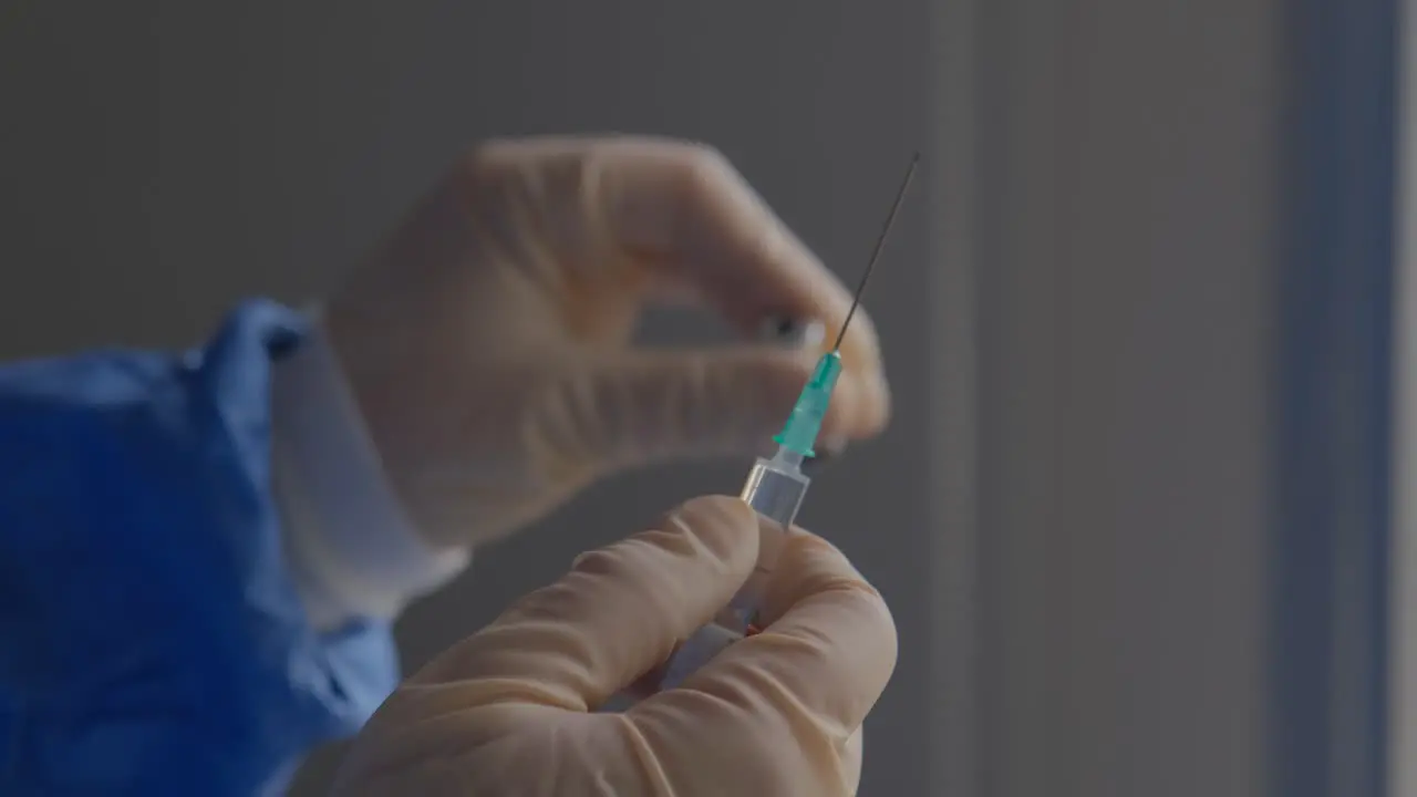 Close-up of a frontline healthcare worker gently shaking a vial of COVID vaccine as they prepare to inoculate patients