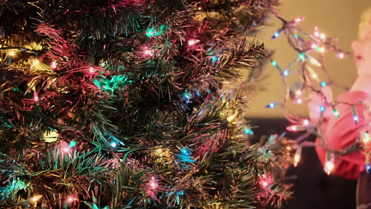 Young caucasian kid helping to decorate Christmas Tree with Christmas Light Close up