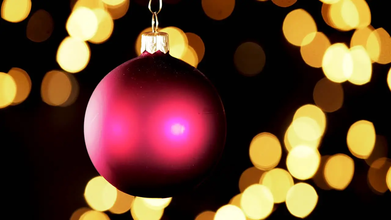 single red Christmas ball ornament with out of focus lights flickering in the background close up