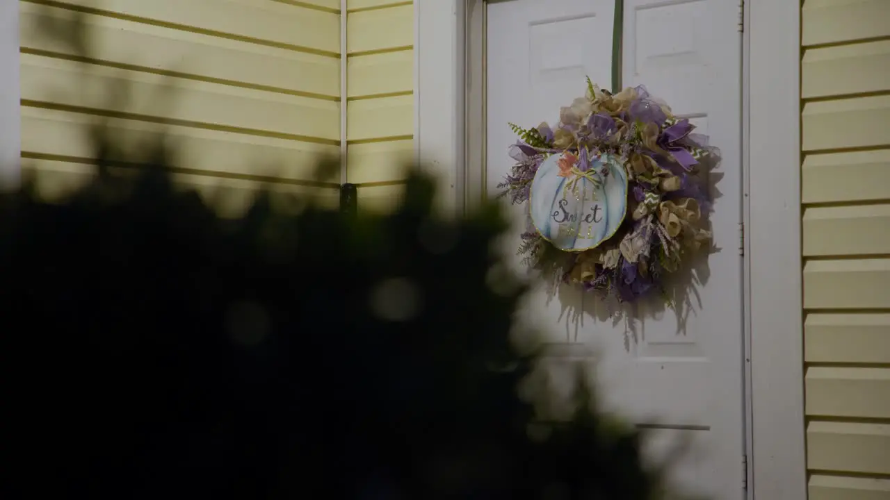 Selective focus on a door with a floral wreath featuring a pumpkin