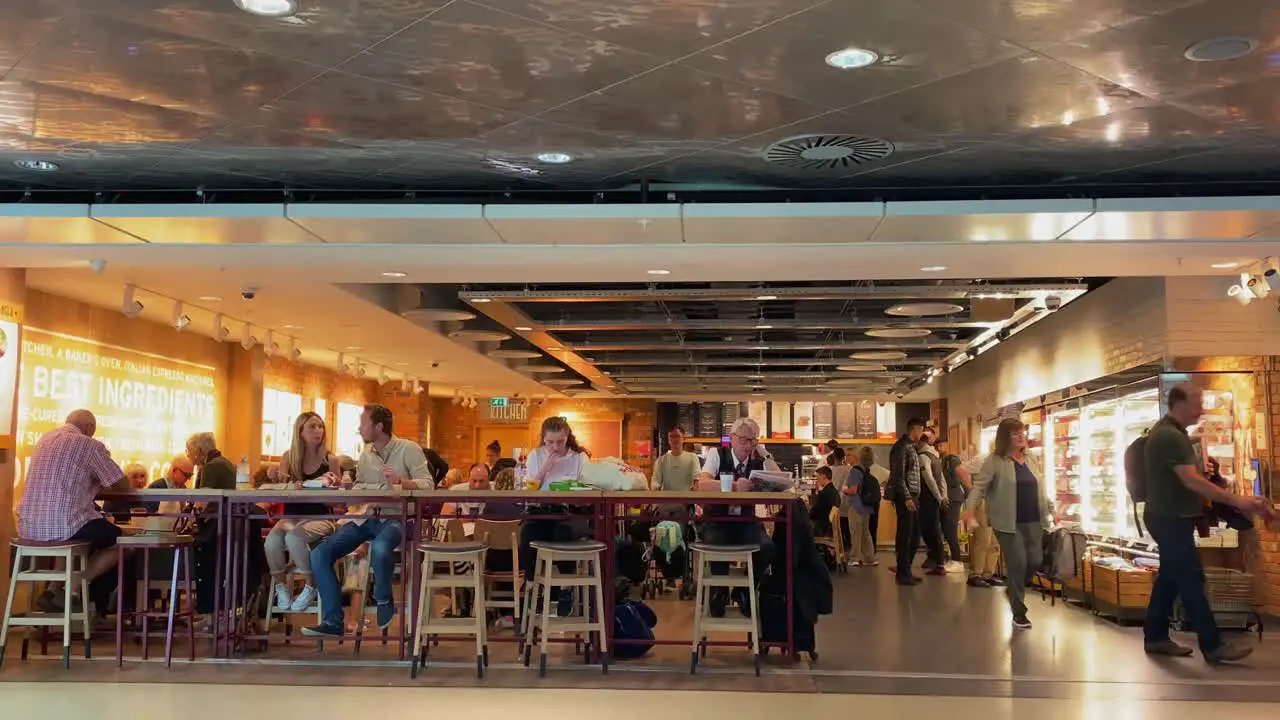 September 2022 Unidentified Travellers Enjoying a Meal Break at Manchester Airport Departures Cafe Prior to Boarding Holiday Flights With Man Walking Through The Scene On His Phone