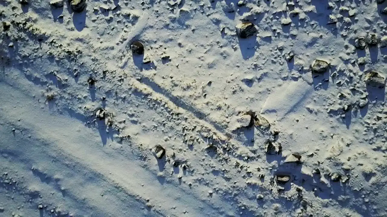 Aerial shot pointed down at volcanic rocks covered in snow