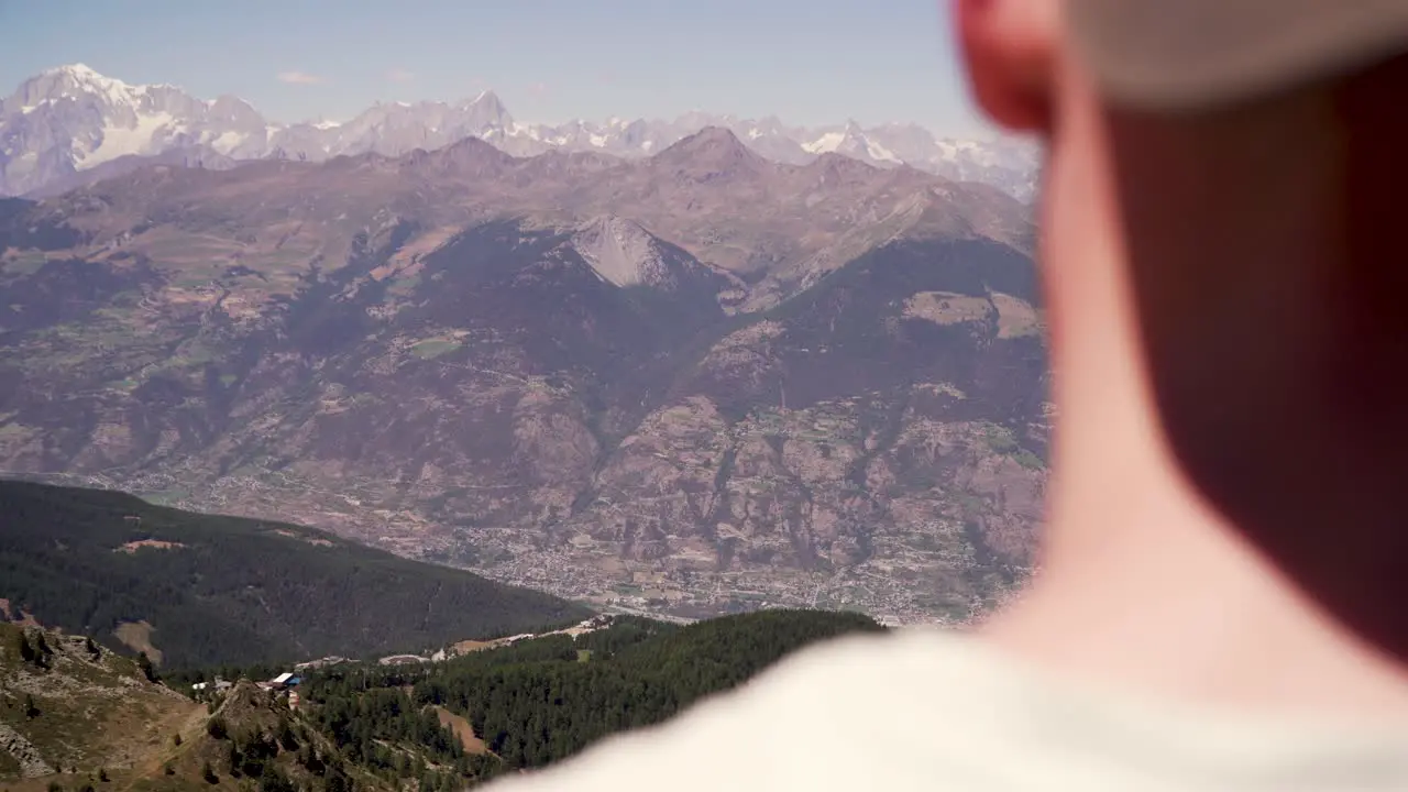 Young man with a cap overlooking the beautiful mountain city of Aosta