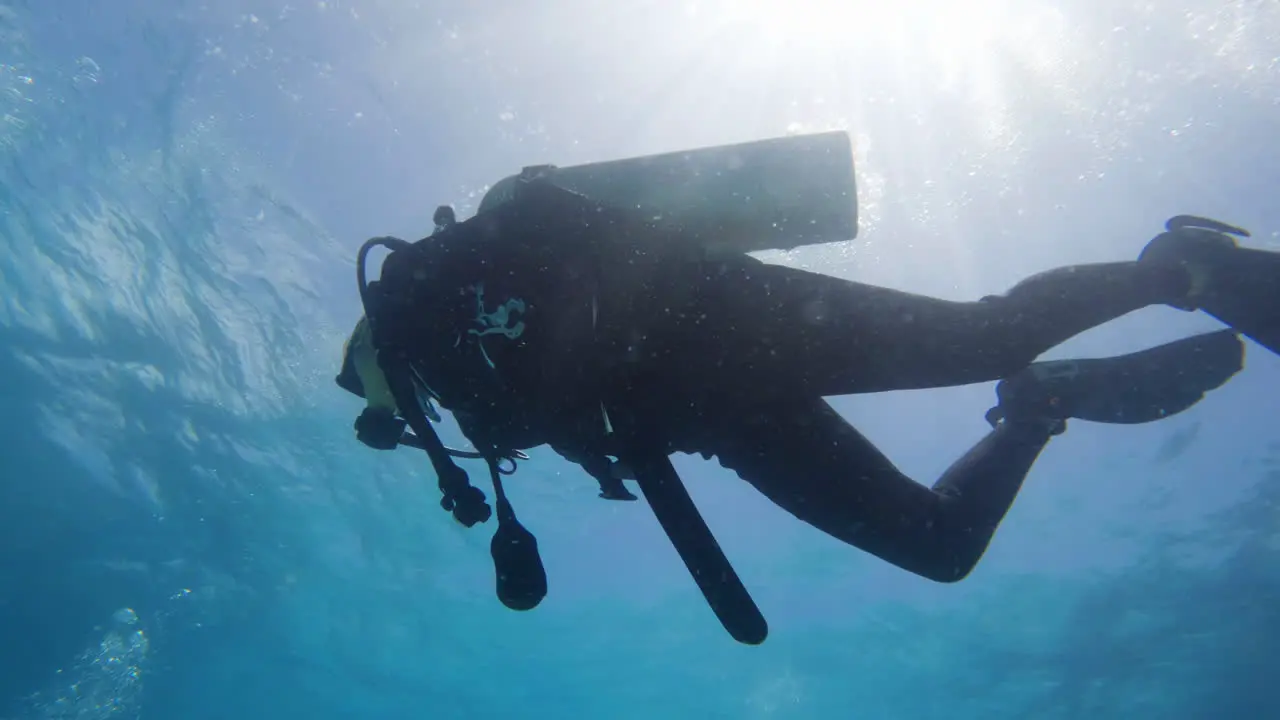 Cinematic underwater shot of a scuba diver against the sunlight in slow motion 4K 120FPS Slomo