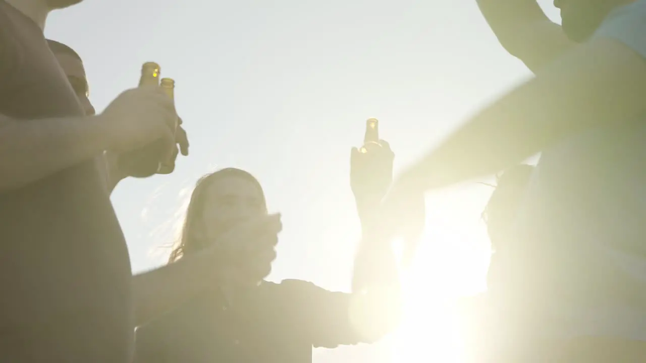 Smiling people clinking beer bottles during party