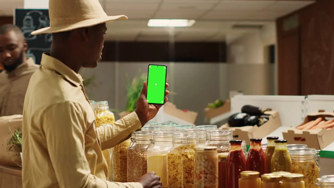 Business owner presenting blank greenscreen display on phone