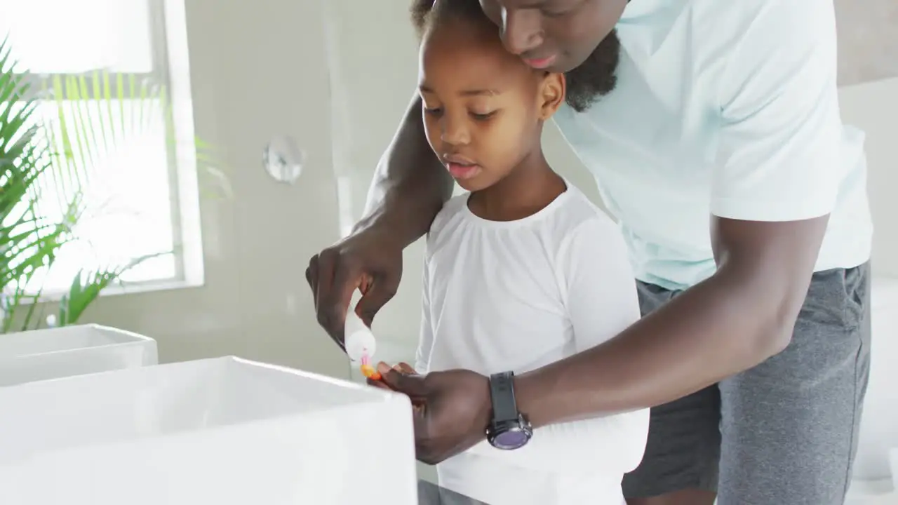 Video of african american father and daughter brushing teeth