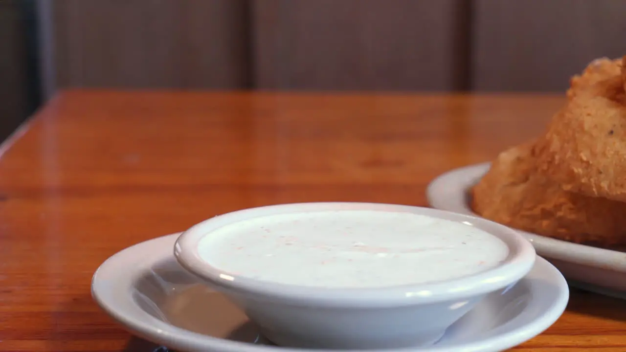 Caucasian hand picks up large deep fried onion ring dips into sauce slider slow motion HD