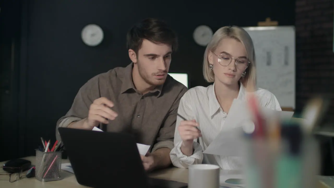 Business couple working on financial project in dark office together