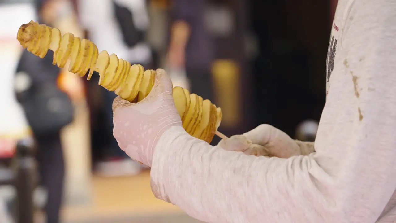 Street vendor preparing Tornado Potato on skewer popular street food