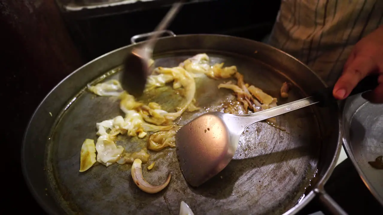 Local Thai cooks Pad Thai on a street food market in a big pan handheld