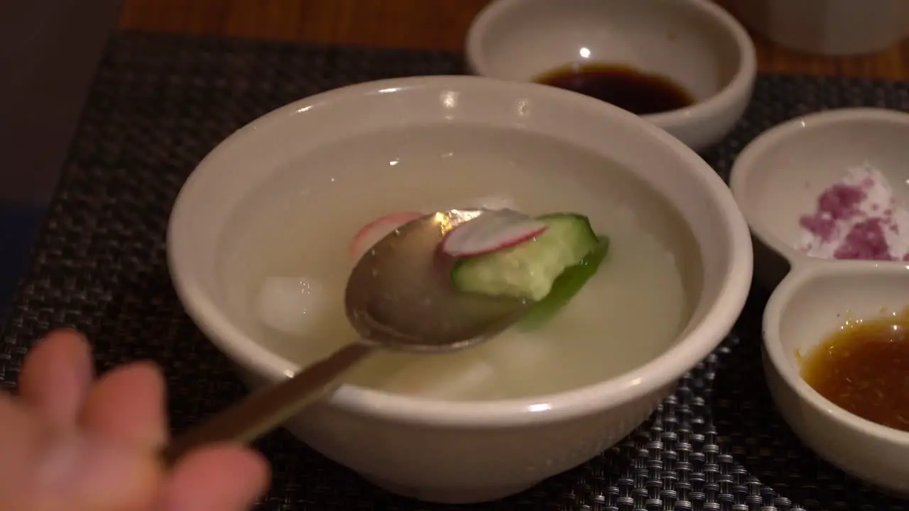 Dongchimi Korean radish water kimchi showing on spoon close-up in restaurant