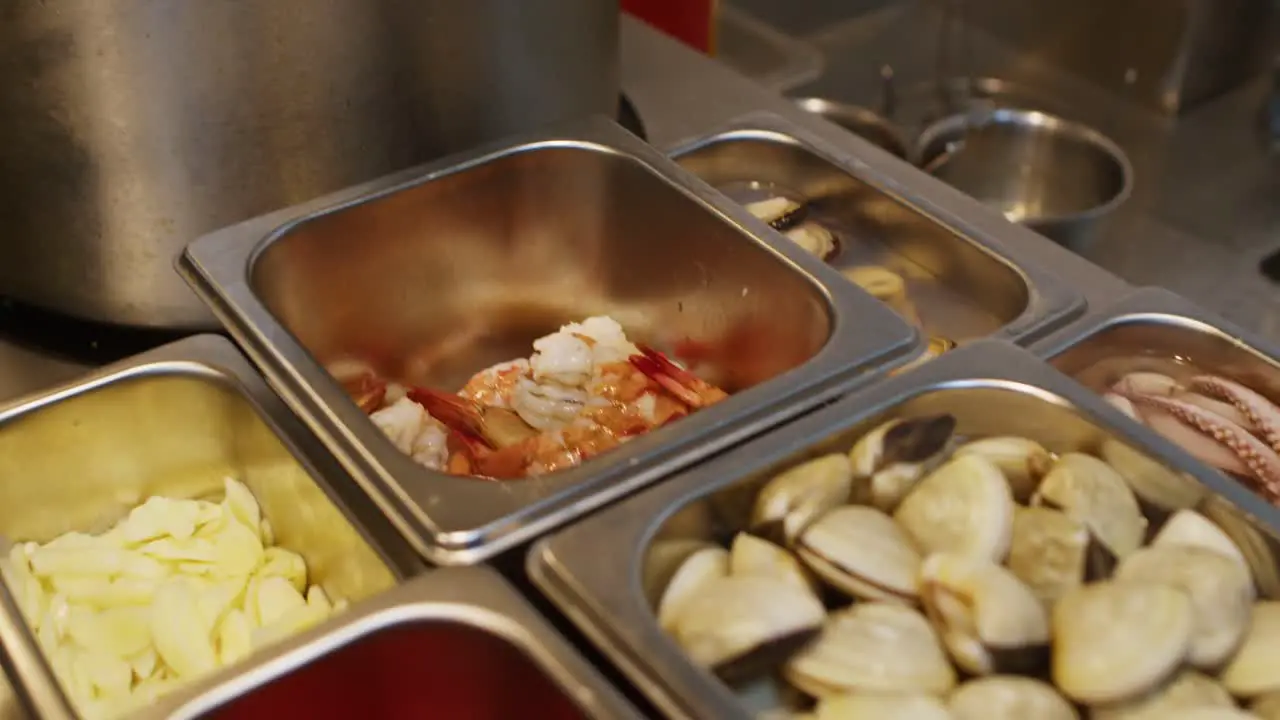 Seafood ingredients for Mediterranean pasta soup preparation in a professional restaurant kitchen