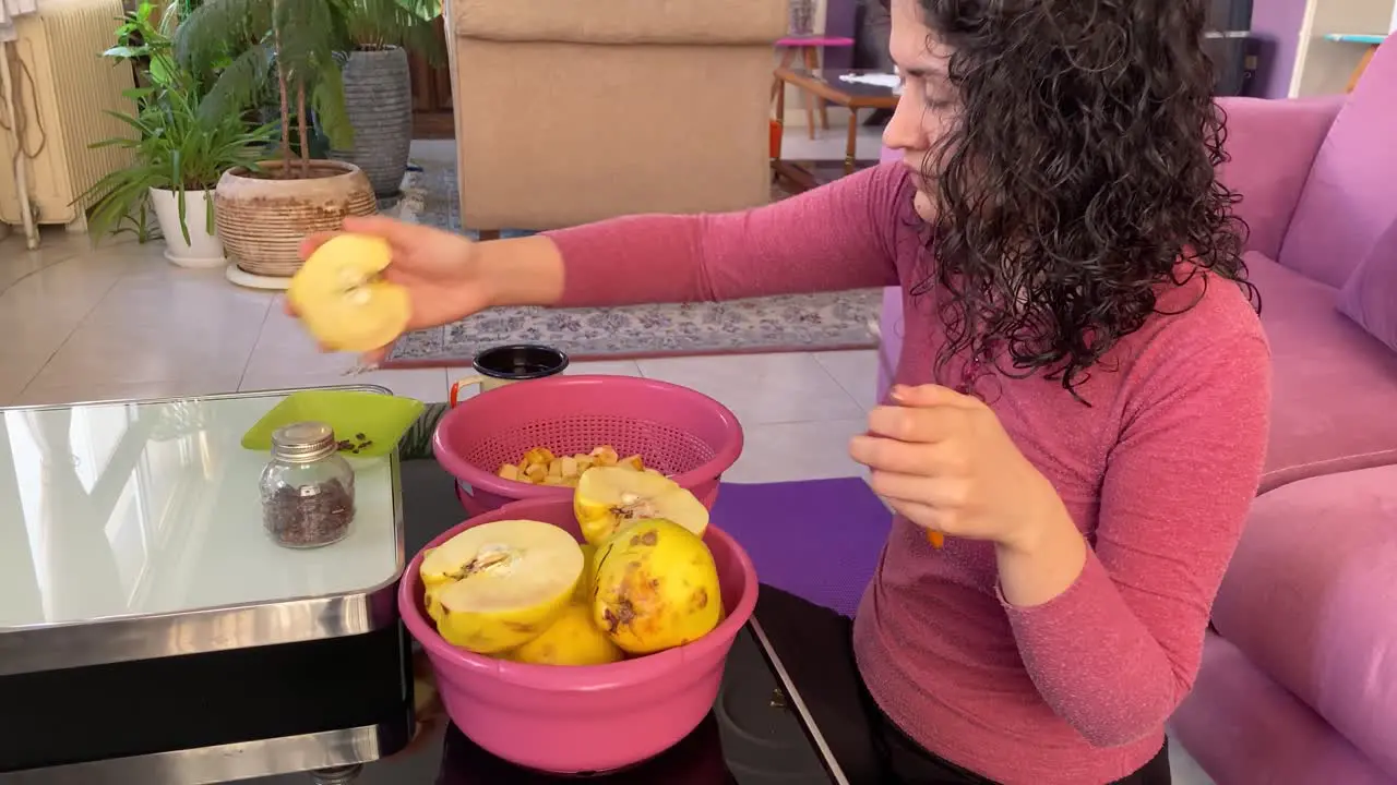 A woman is cutting quince to small pieces to cook with sugar on top of oven fire slow food Persian cuisine then mix with rose water extract and cardamom seeds to marinate jam red slice of delicious