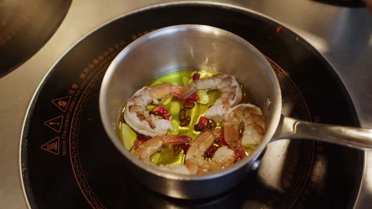 Preparing traditional Mediterranean seafood shrimp soup in a pot inside a professional restaurant kitchen