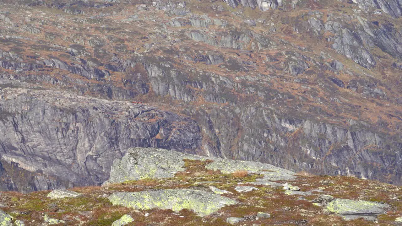 Camera drone hovering above rock and flying towards camera before passing close on left side Drone flying in nature with rocky mountain wall in background Nesheim mountain Vaksdal Norway