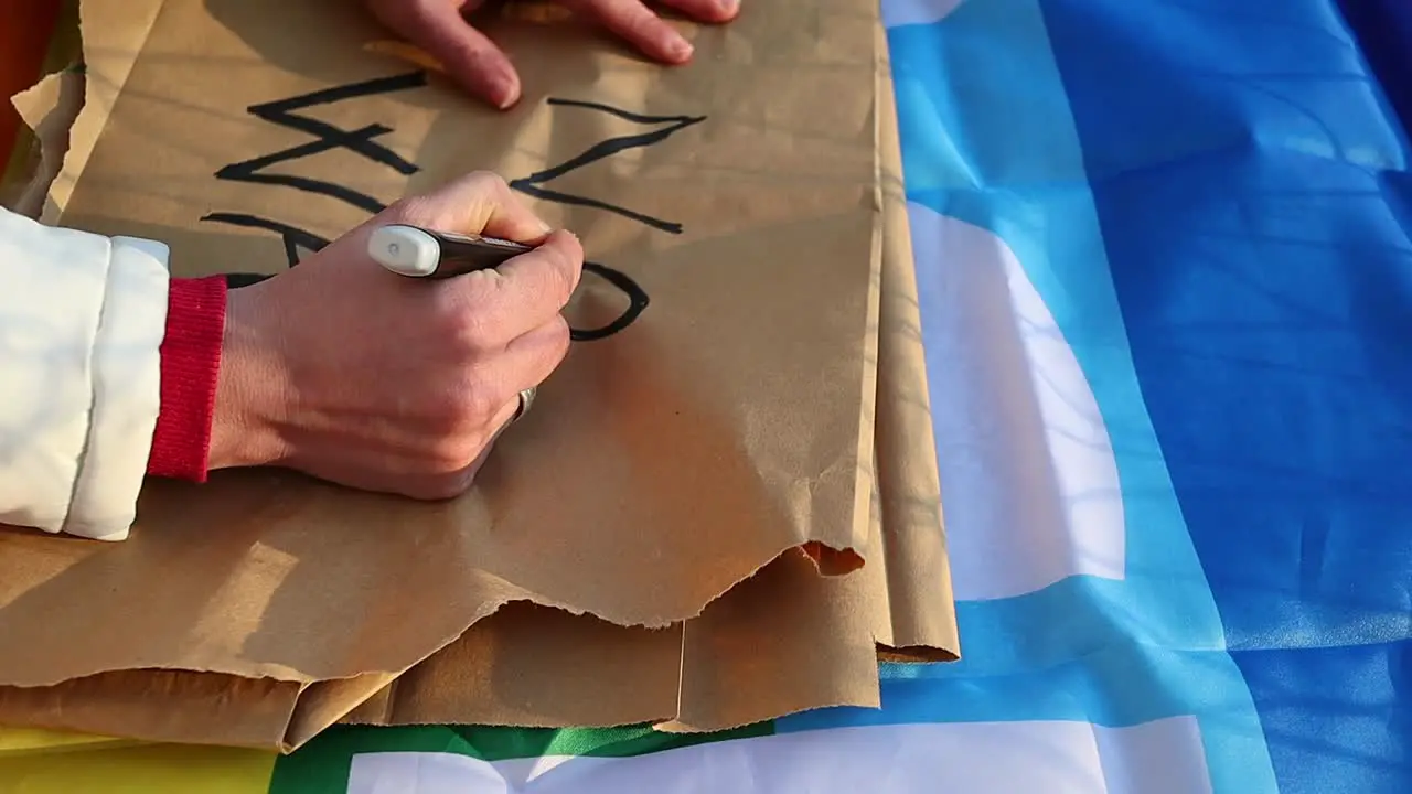 Female caucasian hand writes anti-war protest placard close up shot