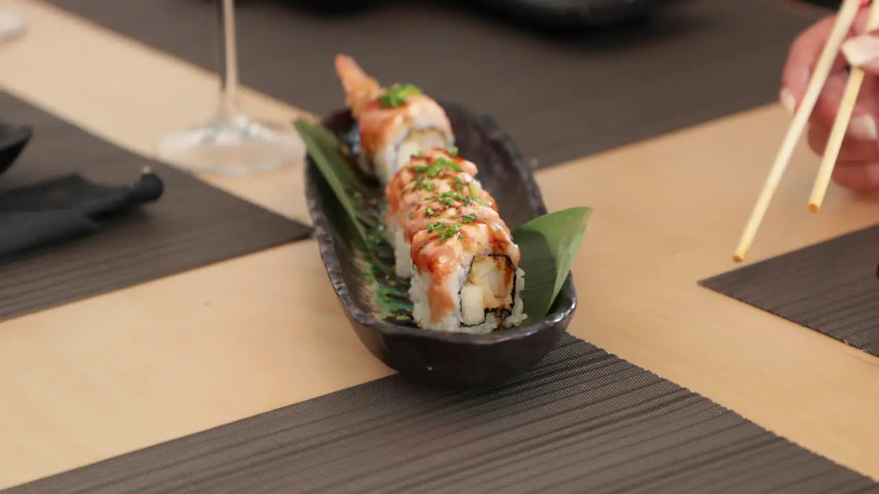 Eating Salmon Sushi Rolls With Shrimp Tempura Using Chopsticks close up