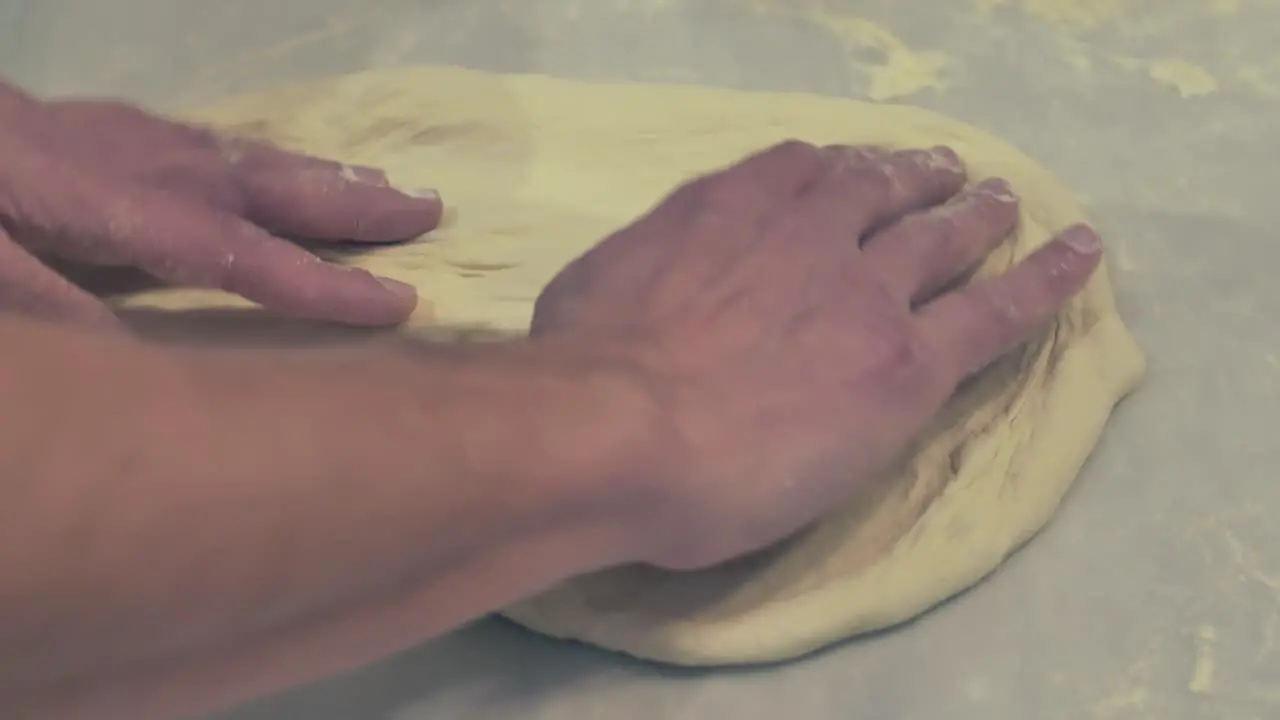 Italian Chef Stretching and turning the Pizza Dough on the table with his bare hands