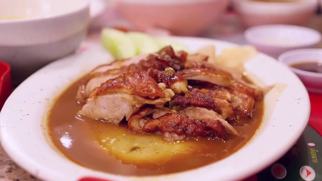 Dipping a slice of Peking duck in a spicy sauce that is served in a platter at a restaurant in Bangkok Thailand