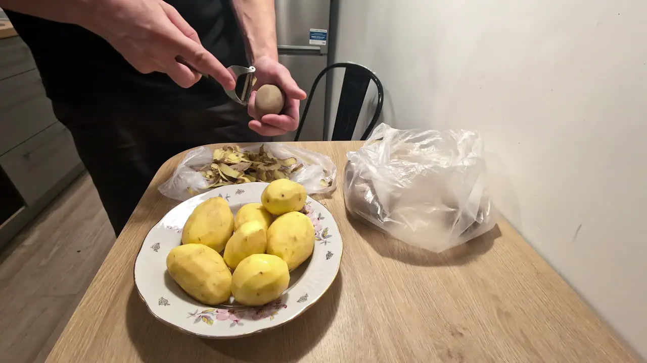 Peeling potatoes skin using potato peeler by hand in the kitchen by chef